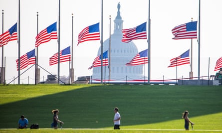 Flags fly at half-staff around the Washington Monument, with the Capitol dome in the background.