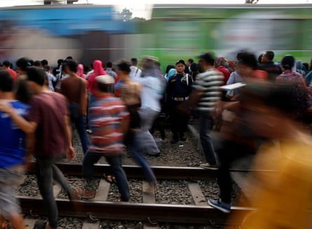 Commuters walks along railway tracks while transferring to another train at Tanah Abang train station in Jakarta