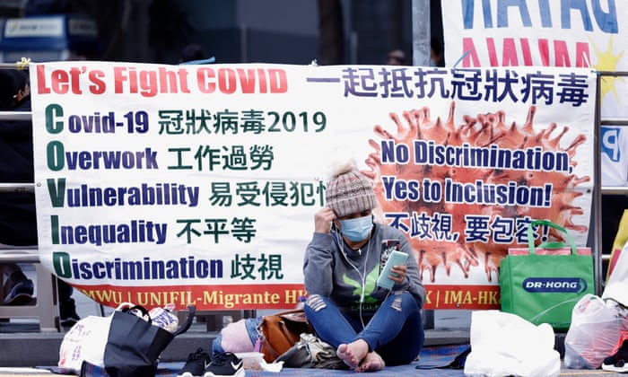 A foreign domestic worker sits in front of slogan banner in Central, Hong Kong.