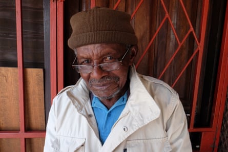 Mofokeng in white coat and brown hat looks at camera
