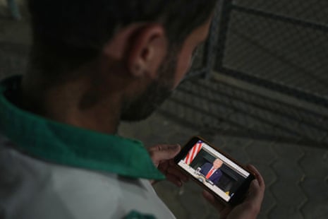 Palestinian paramedic Saeed Awad looks at his phone displaying an image of US president Donald Trump, after the announcement that Israel and Hamas have agreed to the first phase of a ceasefire plan to pause fighting, as he stands at al-Aqsa hospital, in Deir al-Balah, in the central Gaza Strip.