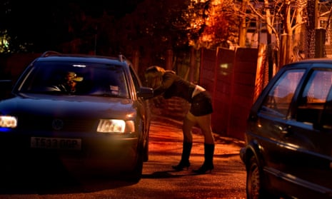 A young woman talks to a man through a car window.