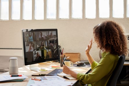 A woman waving to her colleagues on a video call