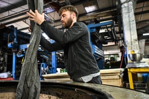 A mill worker handles rolls of Harris tweed cloth