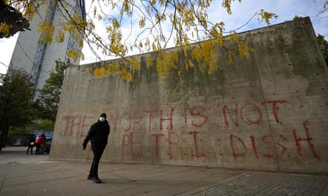 A man wearing a face mask walks past graffiti in Picadilly Gardens, central Manchester.