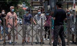 People in lockdown wait behind an entrance gate for their goods to be delivered inside a residential compound in Beijing.