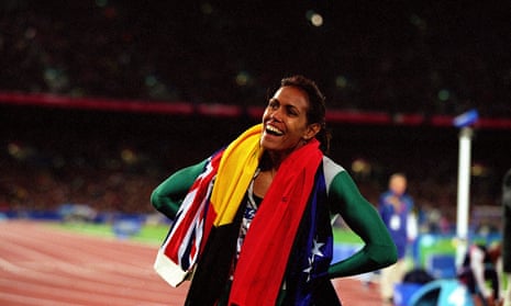 Cathy Freeman on the track with two flags draped around her neck