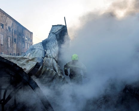 A firefighter walks through the smoke at the site of a warehouse that burned out after it was hit during a night of Russian missile attacks in Kyiv, Ukraine.
