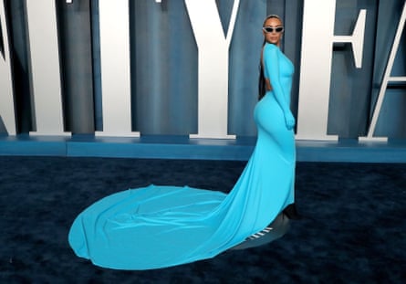 Kim Kardashian, wearing a bright blue dress with a train, shot slightly from behind