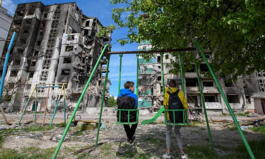 Teenagers Oleskandr and Bohdan sit on swings in front of residential buildings destroyed by Russian forces in the town Borodianka, outside Kyiv.