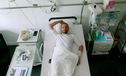 A man lying on a hospital bed listening to music on headphone