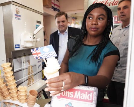 Kemi Badenoch handing over icecream cone next to pile of cones