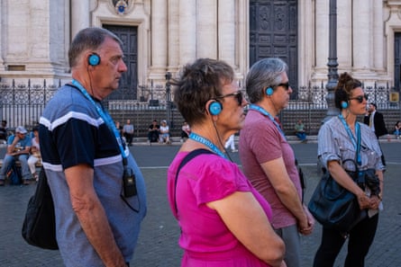 Visitors wearing audio guides cross Piazza Navona