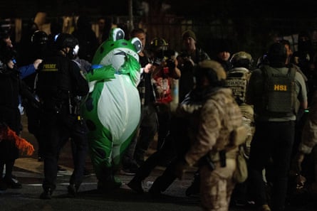 An inflatable frog poses in horror in front of a cluster of law enforcement officers at night