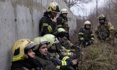 Firefighters hide near a concrete wall during repeated attacks in Kharkiv.