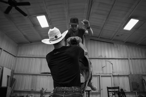 A man helps different man connected a bull simulator inside