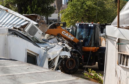 Heavy machinery operates to pull down a white building