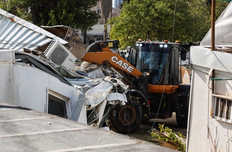 Heavy machinery operates to pull down a white building