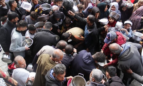 Palestinians gather to receive free food in Jabalia in the northern Gaza Strip, 19 March 2024.