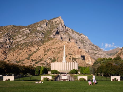 People playing and lounging in the grass in front of a temple