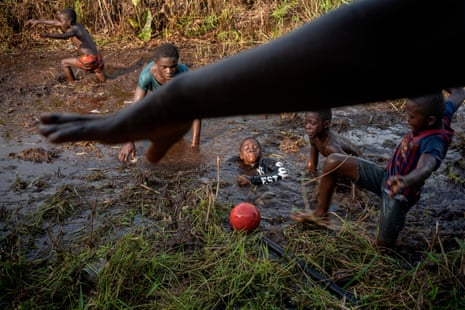 Children playing with a football in a very muddy field