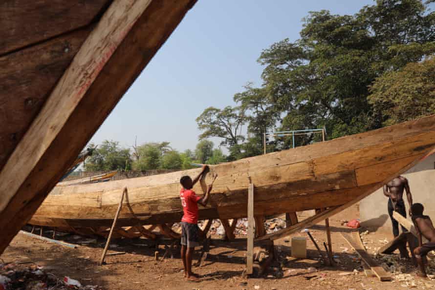Un pescador reparando un bote de madera en el muelle de Tombo.