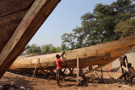 A fisherman repairing a wooden boat at Tombo dock.