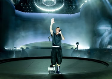 Justin Bieber performs on stage wearing black, holding a mic