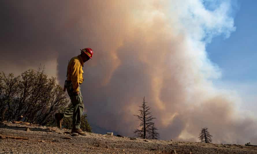 A fire crew member keeps an eye on a hillside as flames roil the Sequoia national forest on 16 September.