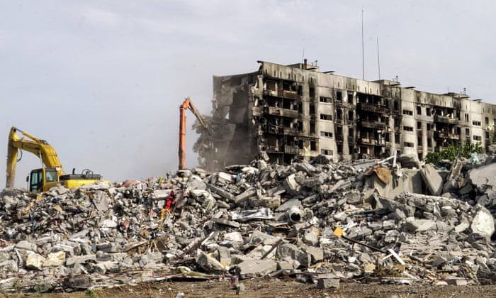 An excavator demolishes ruined buildings in Mariupol.