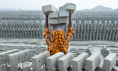 A woman piles bricks on her head at a brick kiln in Bangladesh