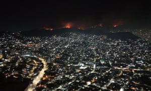 A birds-eye view of a city at night, with a forest fire on the horizon