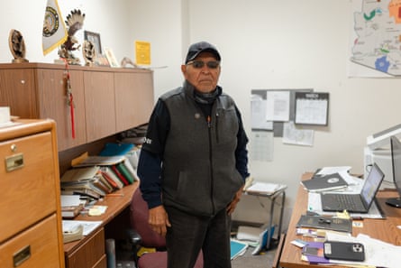 man stands near desk, laptop and cabinets