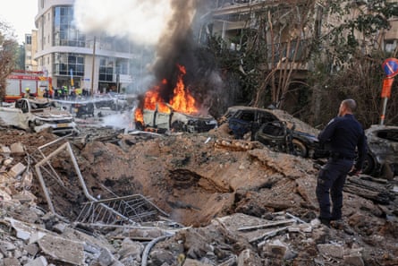 Emergency responder stands next to the crater where a missile struck in