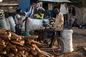 A man buys charcoal from a vendor in the market in Gulu.