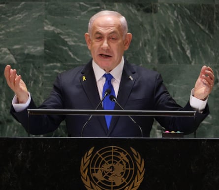 Benjamin Netanyahu, in a suit and tie, speaks at a microphone with both hands raised