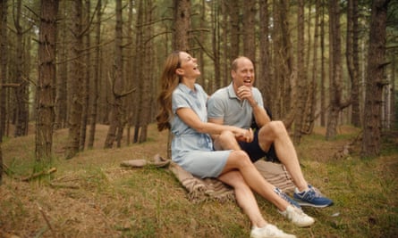Catherine and William laughing while sitting on a blanket in the woods
