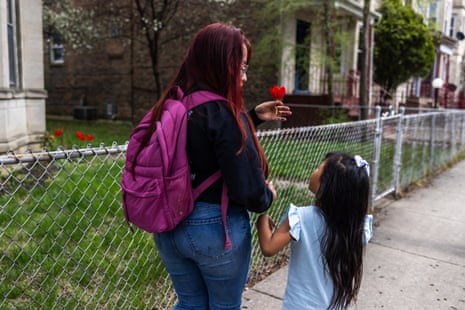 A woman holding a flower and holding the hand of her daughter