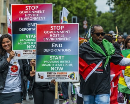 A Windrush protest, with people holding brightly coloured signs calling on the government to stop deporting people