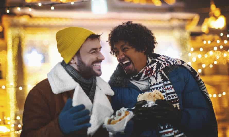 A couple laughing and eating street food (posed by models)