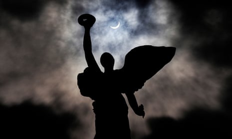 The moon makes its way in front of the sun during a total solar eclipse framed above the angel atop the Princes' Gates, in Toronto, Monday, April 8, 2024. (Frank Gunn/The Canadian Press via AP)