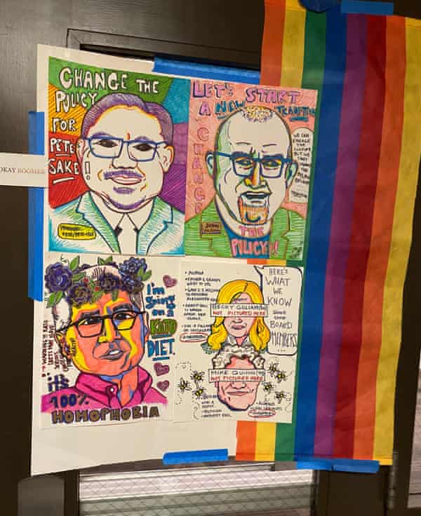 a sign at the sit in, taped to a wall - illustrations of faces in rainbow colors with slogans such as ‘change the policy, for pete’s sake’ and ‘it’s 100% homophobia’