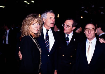 a man stands with his arm around a woman as a man talks to him