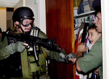Elián González, held by Donato Dalrymple, is taken by US federal agents from his Miami relatives on 22 April 2000.