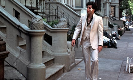 Publicity still from Saturday Night Fever showing Travolta in the street wearing a white suit.
