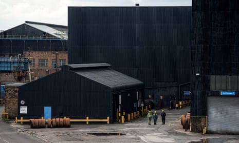 Steelworkers walk through the yard at the Brinsworth Strip Mill in Rotherham, northern England