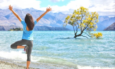 A woman practises yoga by Wanaka’s famous willow on a lake.