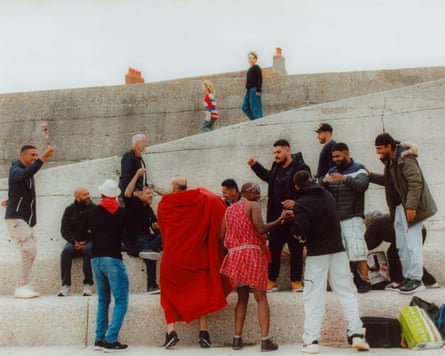 A group of men, many smiling and gesturing, on the beach