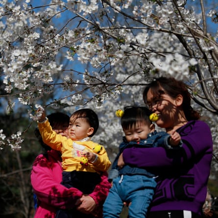 Women and their children look at cherry blossoms in Yuyuantan Park in Beijing, China, 27 March