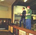 Two teenagers stand on a stage with remote controls in their hands.